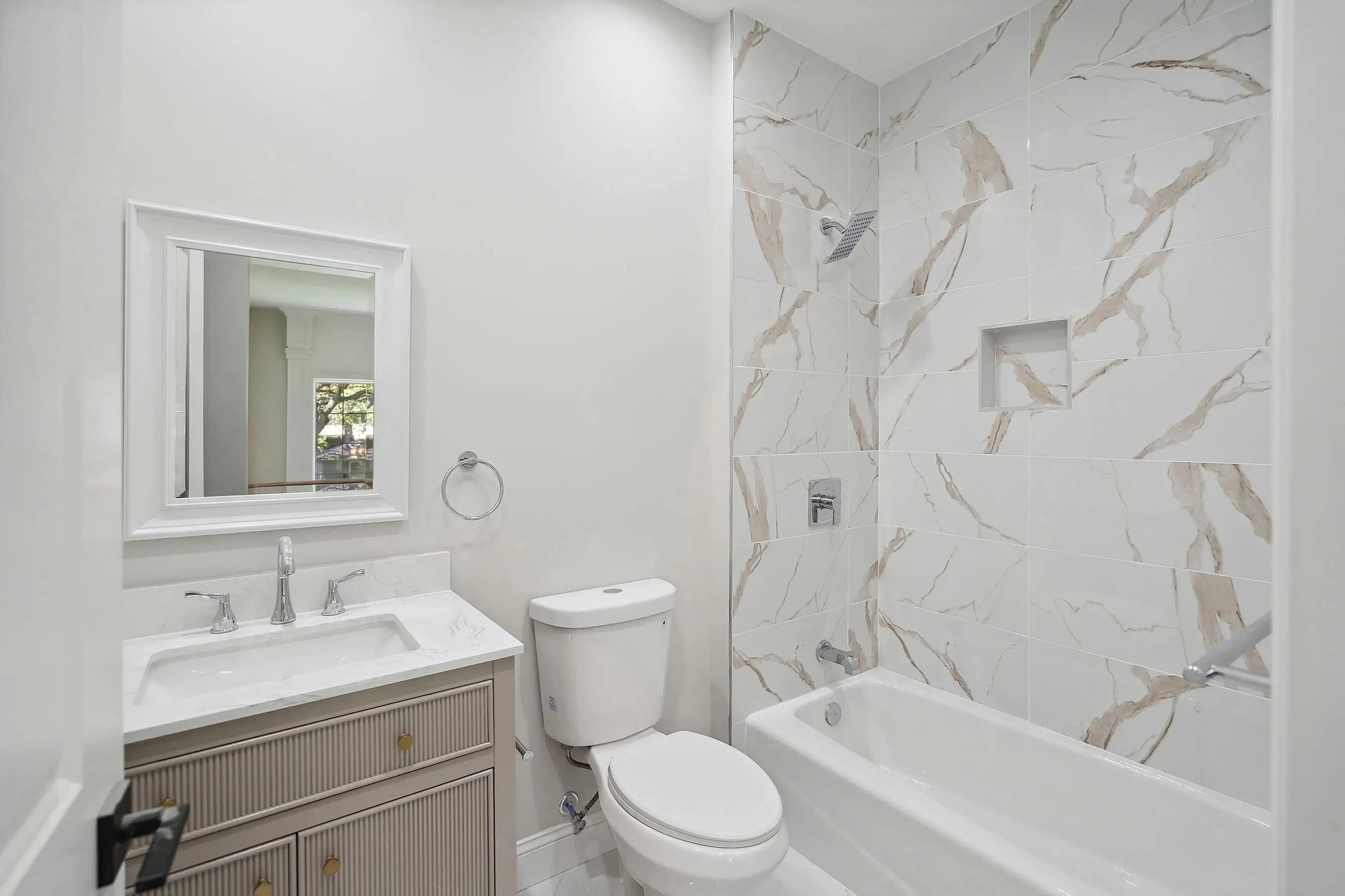 Bathroom with white vanity, toilet, and bathtub with marble-patterned wall. Gallery - Quality Home Distribution
