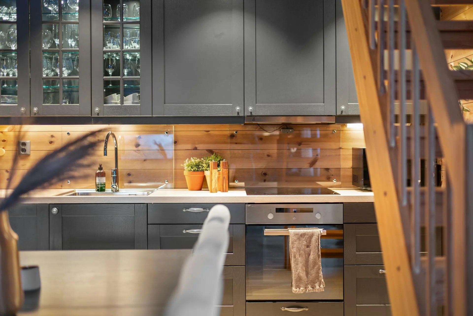 Modern kitchen with gray cabinets, wooden backsplash, and stainless steel appliances. Gallery - Quality Home Distribution